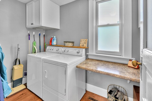 clothes washing area featuring light hardwood / wood-style flooring, cabinets, and washer and clothes dryer