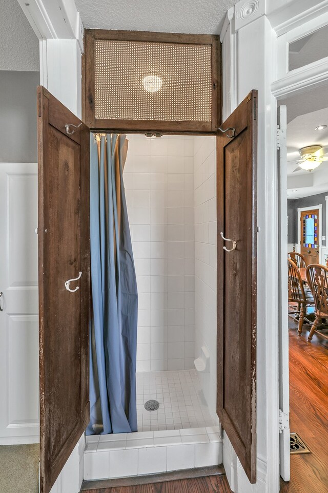 bathroom with hardwood / wood-style floors, tiled shower, and a textured ceiling