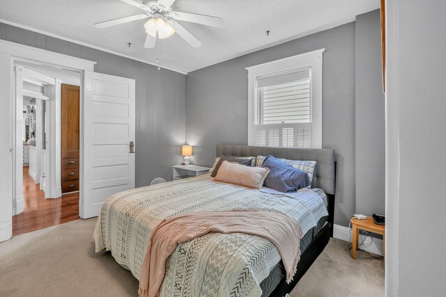 bedroom with ceiling fan, light colored carpet, and a textured ceiling