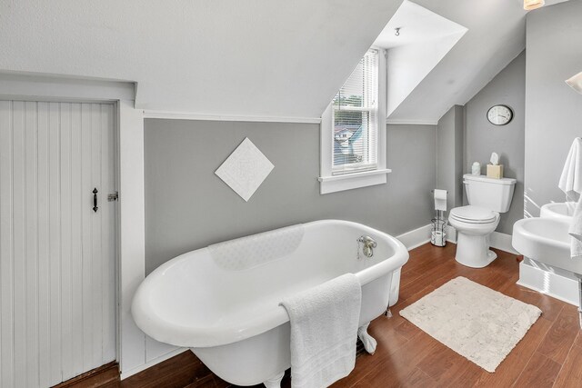 bathroom with hardwood / wood-style floors, toilet, a bathing tub, and vaulted ceiling