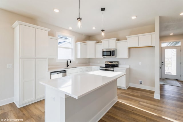 kitchen featuring white cabinets, a kitchen island, light hardwood / wood-style floors, and appliances with stainless steel finishes