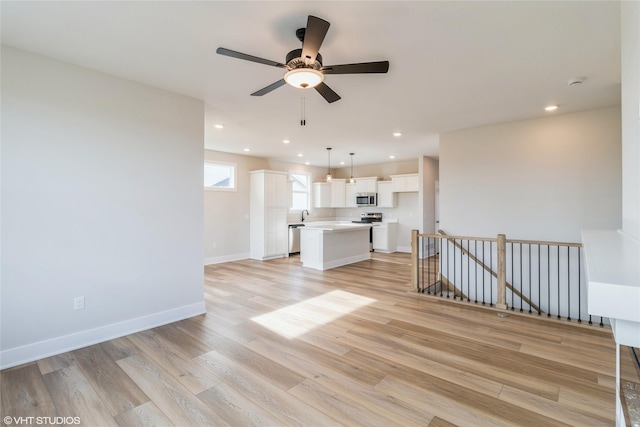 unfurnished living room featuring ceiling fan and light hardwood / wood-style floors