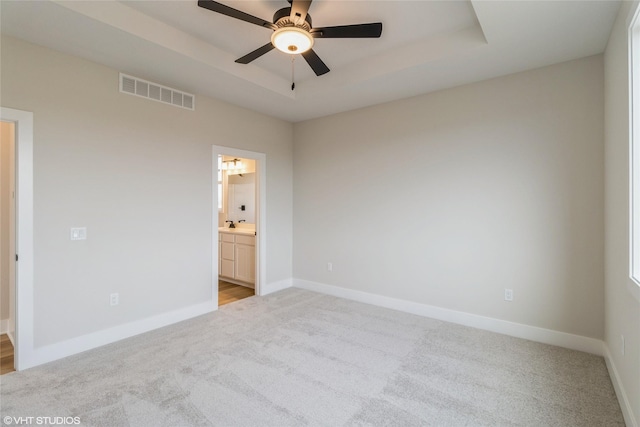 unfurnished bedroom with light carpet, ensuite bath, and ceiling fan