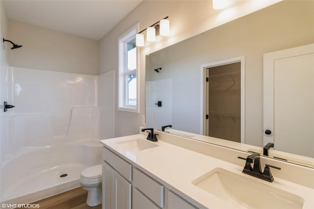 bathroom featuring toilet, vanity, wood-type flooring, and walk in shower