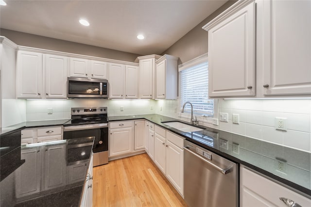 kitchen with decorative backsplash, appliances with stainless steel finishes, sink, light hardwood / wood-style flooring, and white cabinets