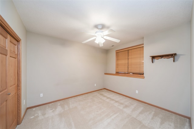 unfurnished bedroom with light carpet, a textured ceiling, a closet, and ceiling fan