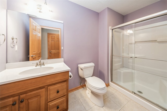 bathroom featuring tile patterned flooring, vanity, toilet, and a shower with shower door