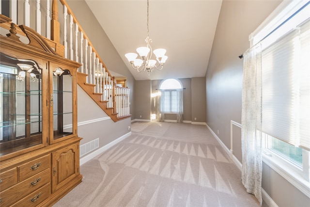 unfurnished dining area with a chandelier, light colored carpet, and high vaulted ceiling