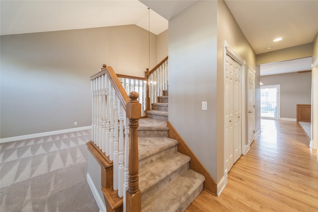 stairs featuring hardwood / wood-style floors and lofted ceiling