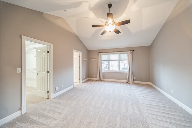 unfurnished bedroom with lofted ceiling, light carpet, a walk in closet, ceiling fan, and a closet