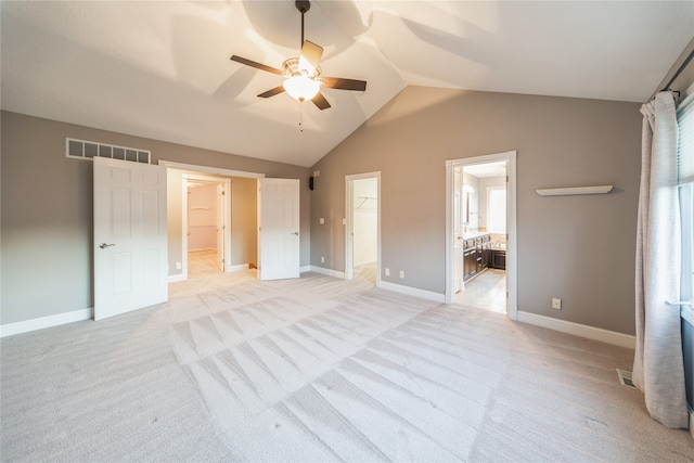 unfurnished bedroom featuring a walk in closet, ensuite bath, vaulted ceiling, ceiling fan, and a closet