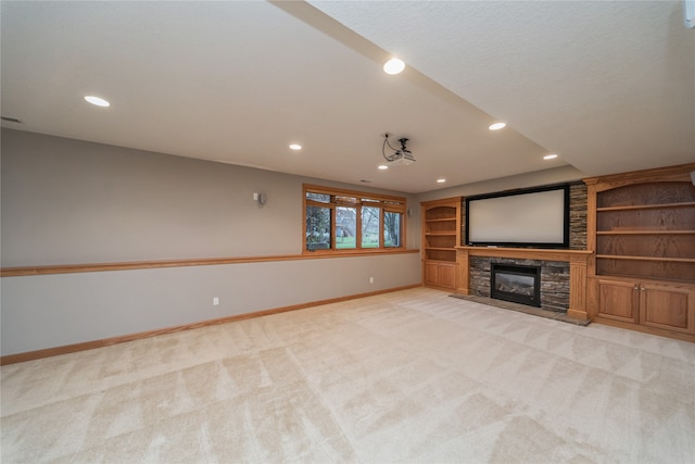 home theater room featuring a stone fireplace and light colored carpet