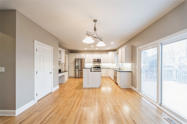 kitchen with light hardwood / wood-style flooring, white cabinets, pendant lighting, and appliances with stainless steel finishes