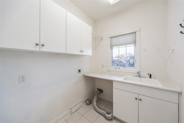 clothes washing area featuring cabinets, light tile patterned floors, electric dryer hookup, and sink