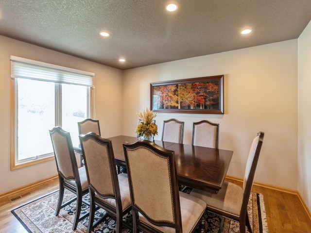 dining room with a textured ceiling, light wood-type flooring, and a wealth of natural light