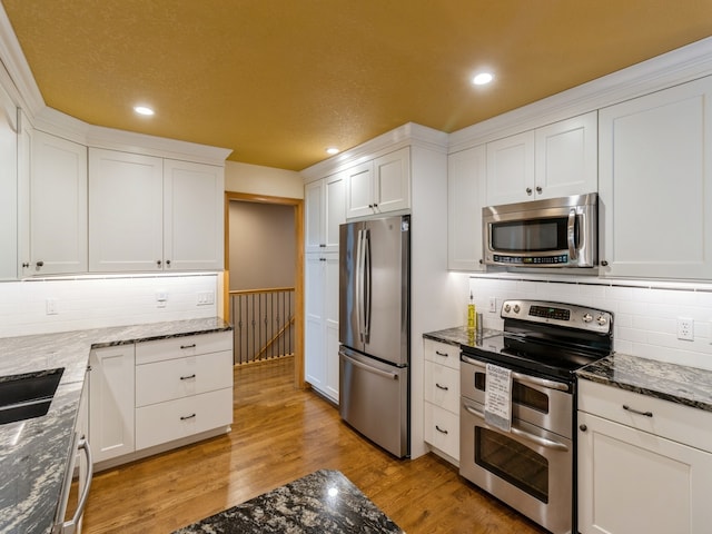 kitchen with white cabinets, stainless steel appliances, and light hardwood / wood-style floors