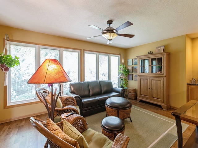 living room featuring a textured ceiling, wood-type flooring, and ceiling fan