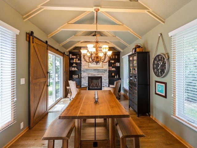 unfurnished dining area with hardwood / wood-style flooring, lofted ceiling with beams, a notable chandelier, a fireplace, and a barn door