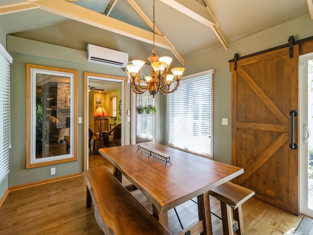 dining space featuring vaulted ceiling, a barn door, hardwood / wood-style floors, a wall mounted air conditioner, and a notable chandelier