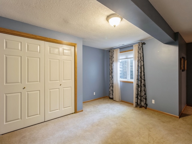 unfurnished bedroom with light carpet, a closet, and a textured ceiling