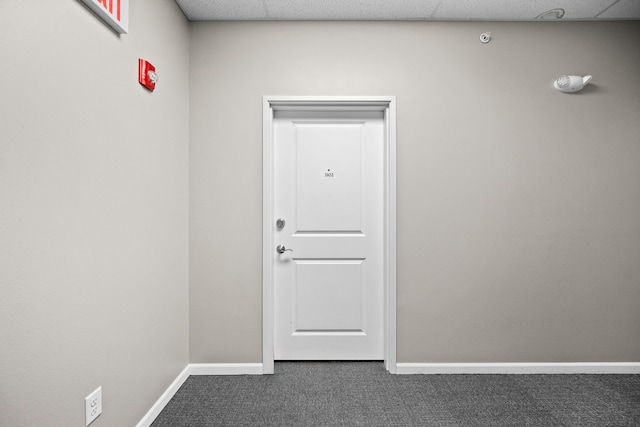 interior space featuring dark carpet and a paneled ceiling