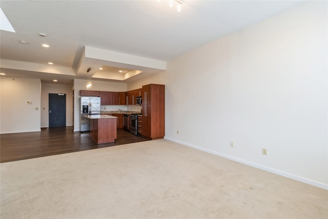 kitchen featuring a raised ceiling, dark hardwood / wood-style flooring, a breakfast bar, a kitchen island, and appliances with stainless steel finishes