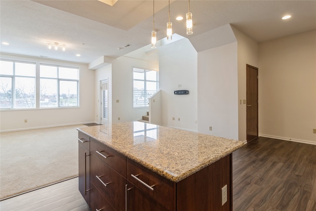 kitchen featuring plenty of natural light, a center island, dark wood-type flooring, and hanging light fixtures