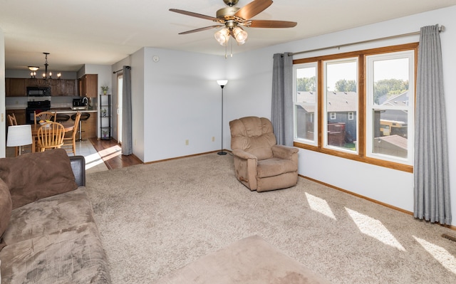 living room featuring ceiling fan with notable chandelier and hardwood / wood-style flooring