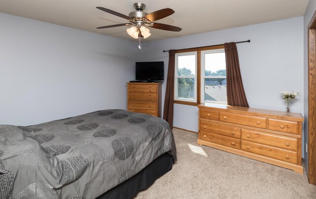 carpeted bedroom featuring ceiling fan and a textured ceiling