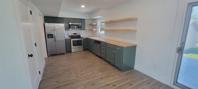 kitchen with appliances with stainless steel finishes, light wood-type flooring, and sink