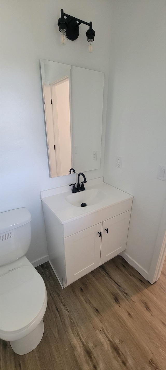 bathroom featuring wood-type flooring, vanity, and toilet