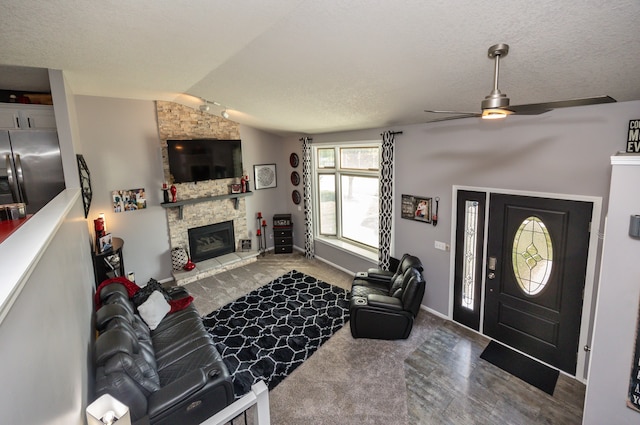 carpeted living room with ceiling fan, a stone fireplace, a textured ceiling, and vaulted ceiling