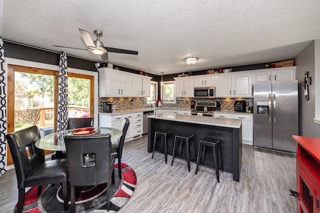 kitchen featuring ceiling fan, white cabinets, stainless steel appliances, and a center island