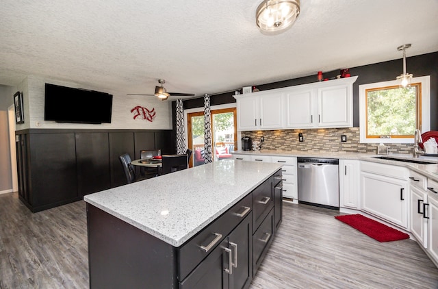 kitchen with a kitchen island, dishwasher, ceiling fan, and white cabinetry