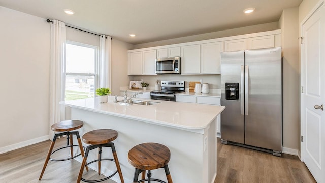 kitchen featuring a center island with sink, light hardwood / wood-style floors, white cabinets, and stainless steel appliances