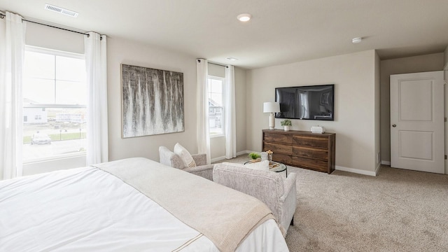 bedroom featuring light colored carpet and multiple windows