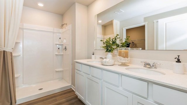 bathroom with hardwood / wood-style floors, vanity, and walk in shower