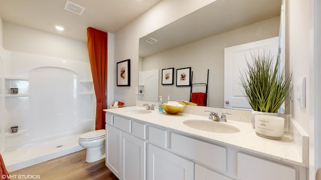 bathroom featuring hardwood / wood-style floors, vanity, toilet, and walk in shower