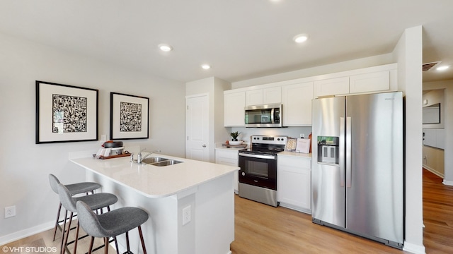 kitchen featuring white cabinets, light wood-type flooring, stainless steel appliances, and sink