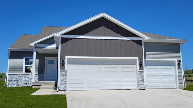 2418 Butler Dr, Adel, IA 50003 - view of front of home featuring stone siding, a front yard, and an attached garage