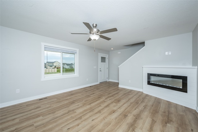 unfurnished living room featuring light wood-type flooring, a textured ceiling, and ceiling fan