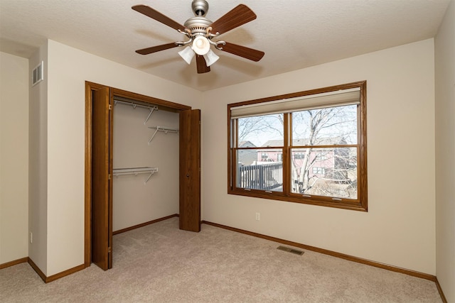 unfurnished bedroom featuring light carpet, a closet, and ceiling fan