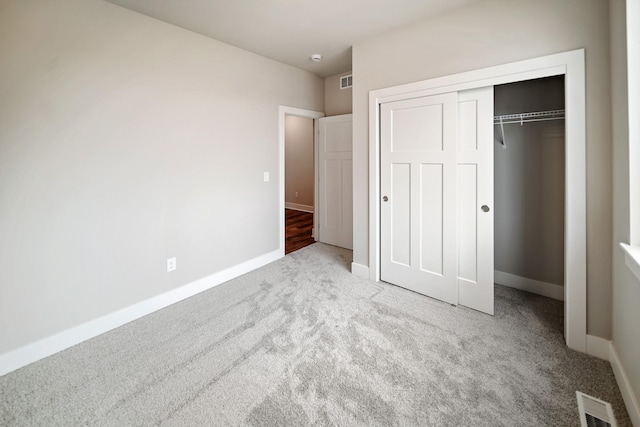 unfurnished bedroom with light carpet and a closet