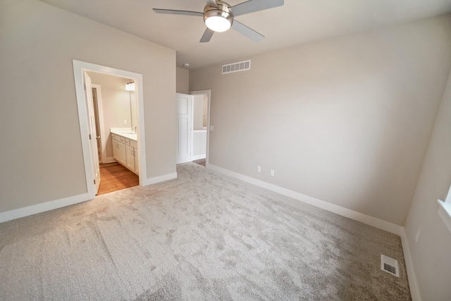 unfurnished bedroom featuring ceiling fan, light colored carpet, and connected bathroom