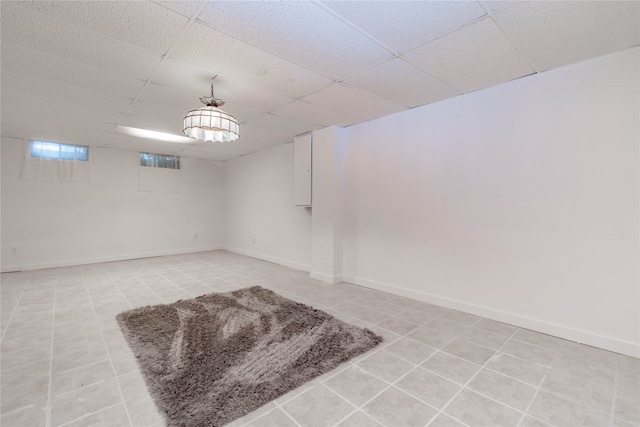 basement with a paneled ceiling and light tile patterned floors