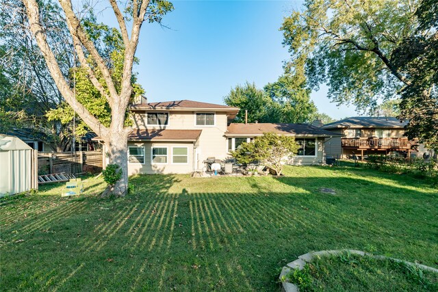 back of property featuring a storage unit, a wooden deck, a patio area, and a yard