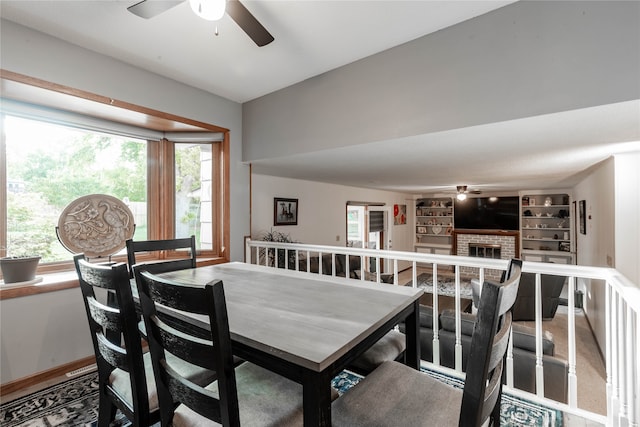 dining area featuring ceiling fan, a fireplace, and a healthy amount of sunlight