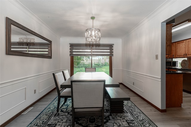 dining area with wood-type flooring, a notable chandelier, and ornamental molding