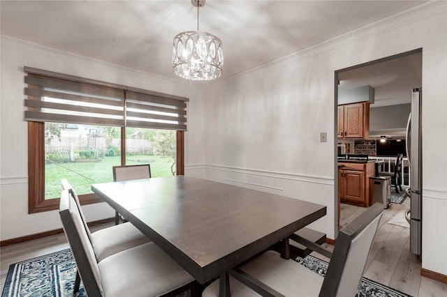 dining space featuring light hardwood / wood-style floors, ornamental molding, and an inviting chandelier