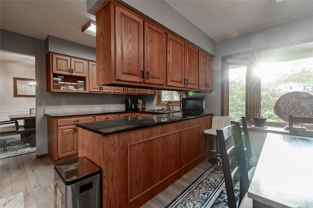 kitchen featuring sink, dark stone counters, light hardwood / wood-style floors, and a wealth of natural light